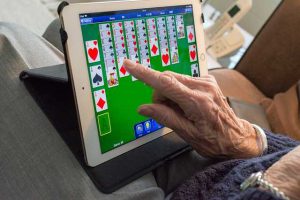 IT-für-Senioren Oma spielt Karten am Tablett